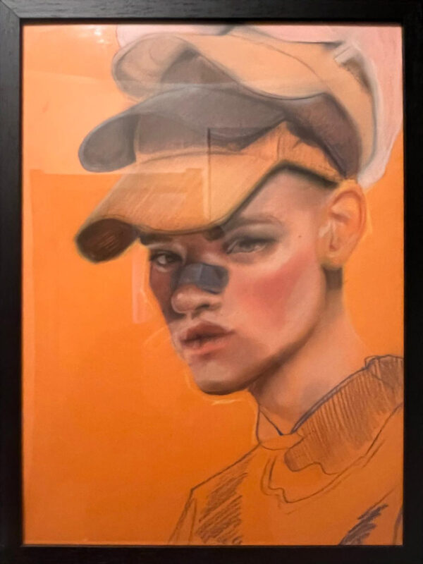 Ritratto a pastello su carta arancione raffigurante un giovane con cappello, studio realistico con accenti contemporanei. Disegno di SOME®, 2025.